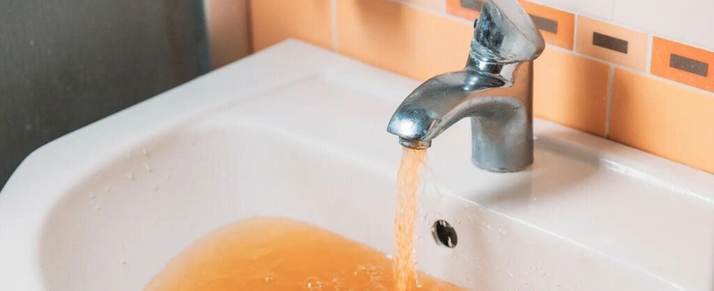 ржавая вода течет из крана в раковину